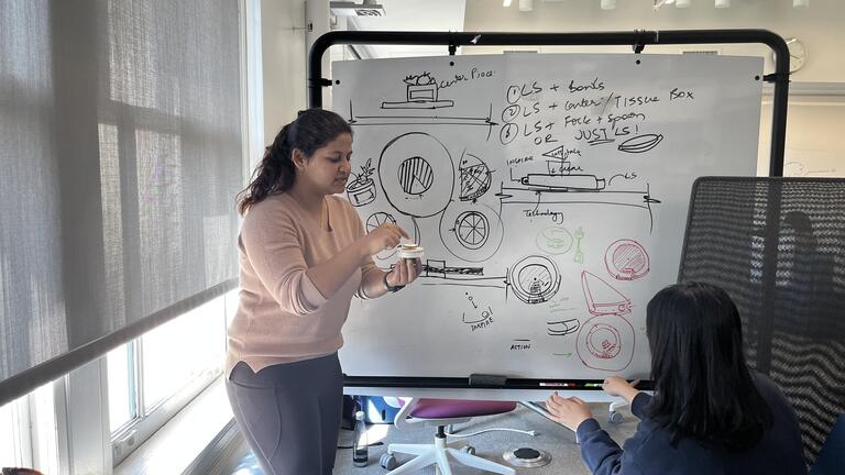Two master's students working at a whiteboard