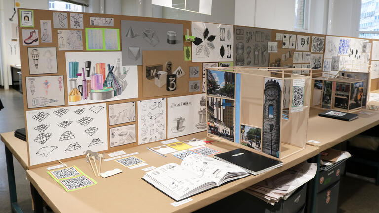 A desk in a studio filled with student work