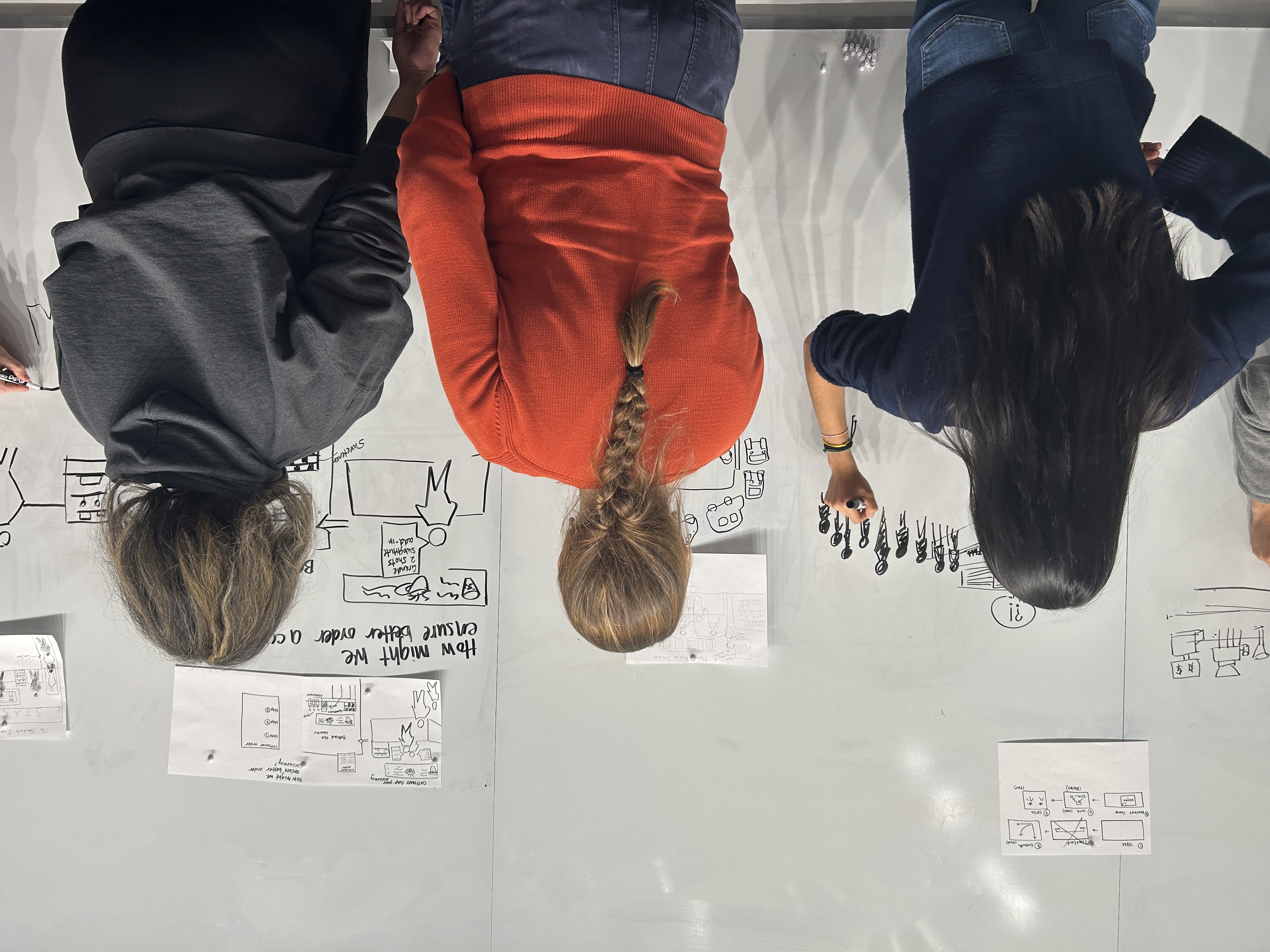 students stand at the whiteboard drawing diagrams