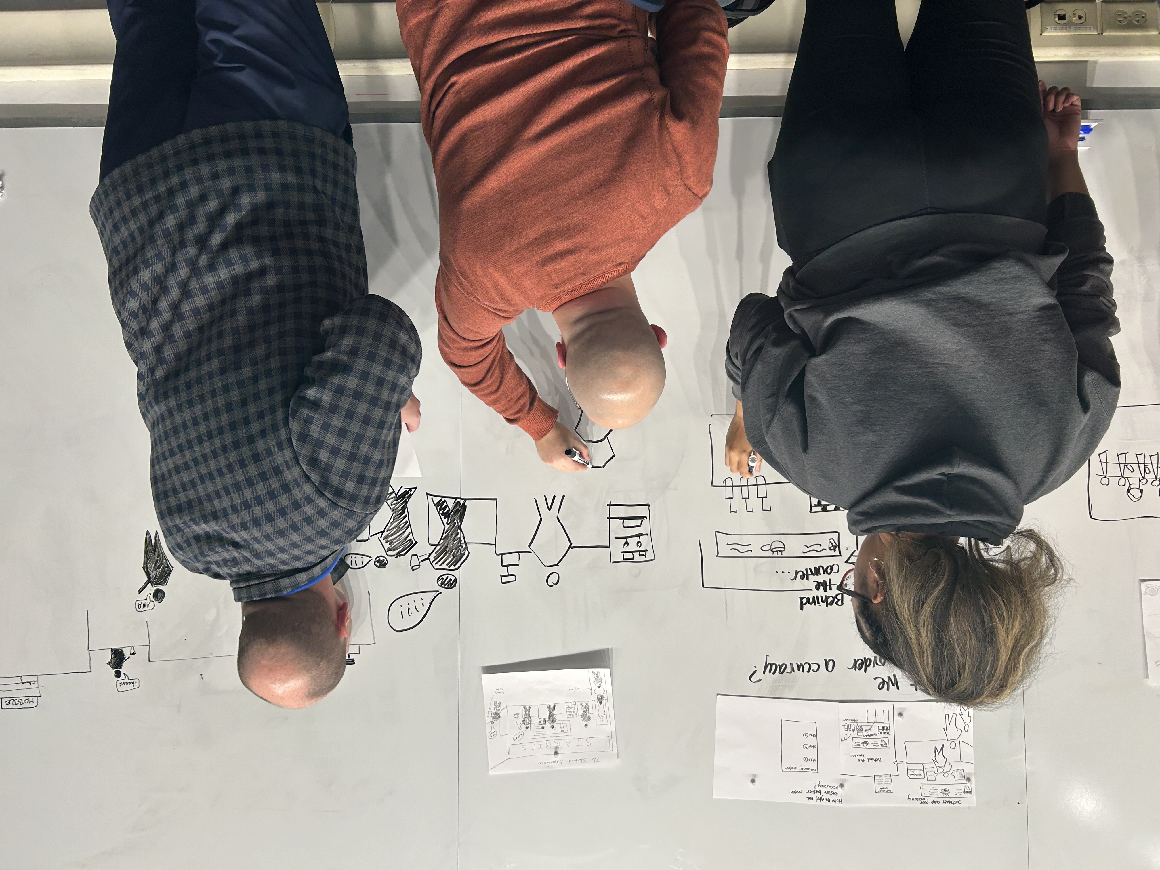 students stand at the whiteboard drawing diagrams together
