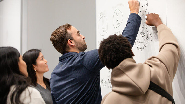 students draw together at the whiteboard