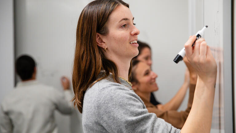 an MBA student draws a diagram at the whiteboard