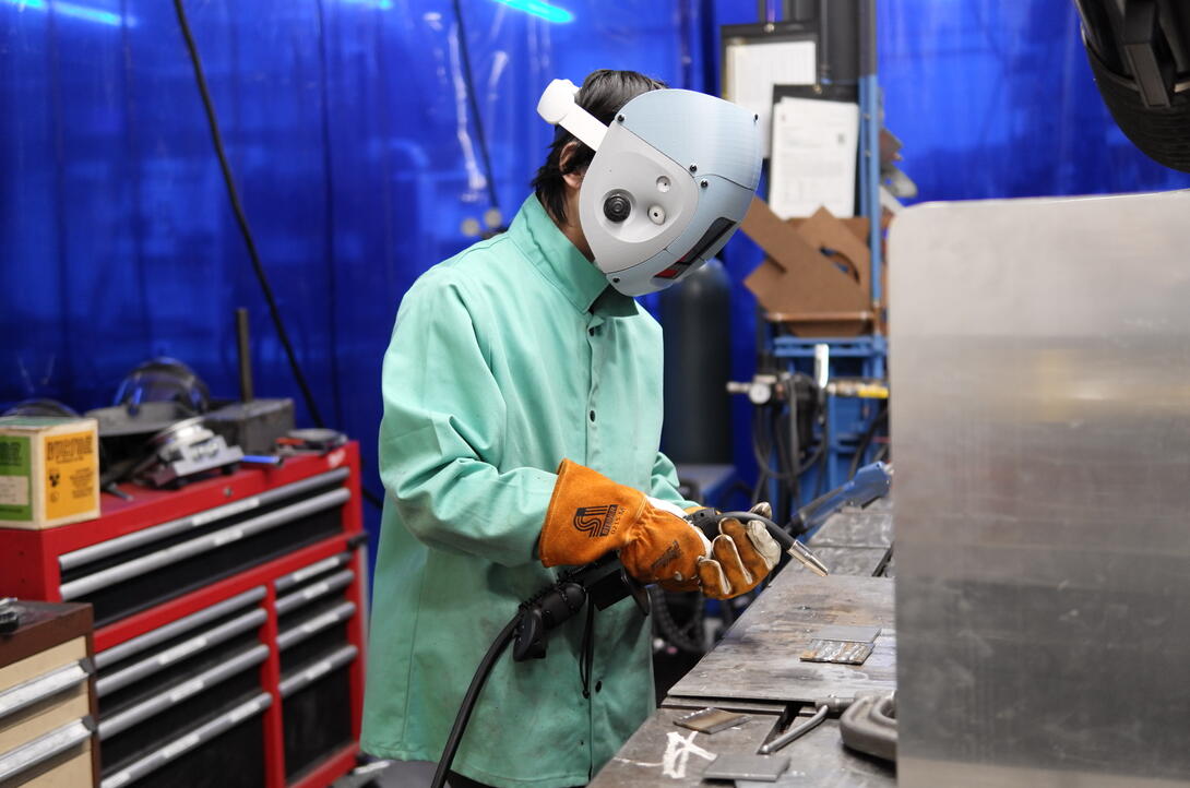 A man welding metal in a mask