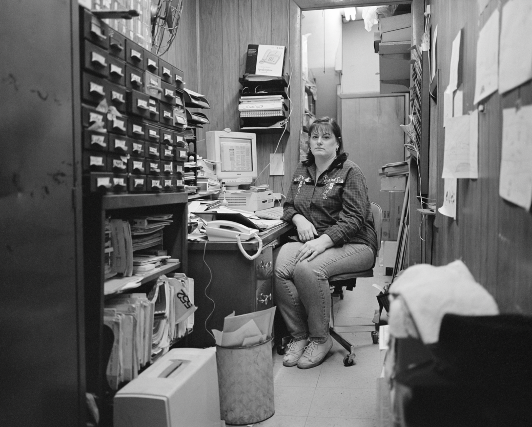 A woman in a cluttered office photographed by Dylan Vitone