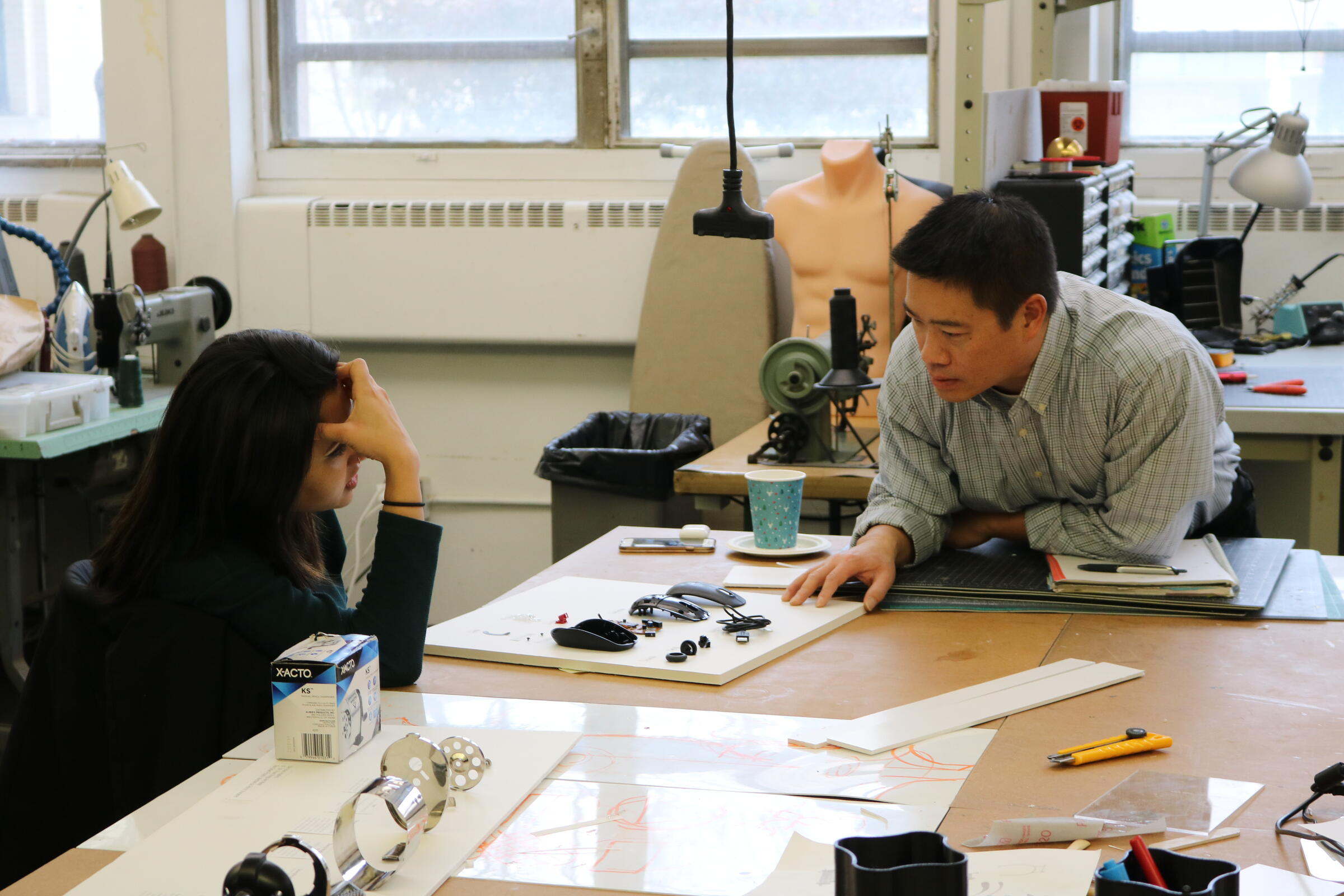 Wayne Chung going over the parts to a computer mouse with a student.