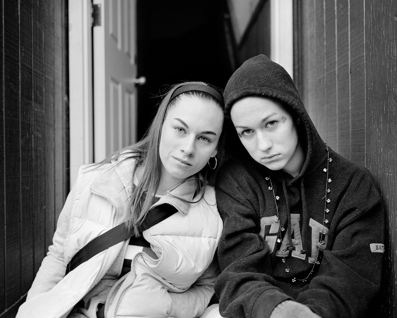 Two girls sitting next to each other photographed by Dylan Vitone